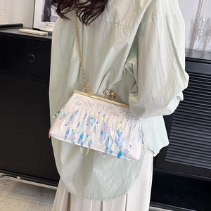 White sequin tassel evening clutch bag with gold chain strap worn by a female model