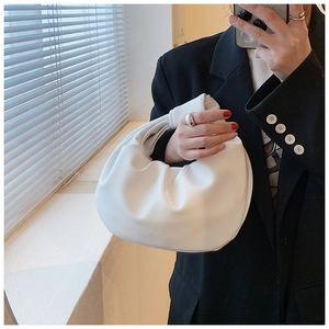 Detail of white pleated cloud bag with unique knotted handle and minimalist vegan leather texture