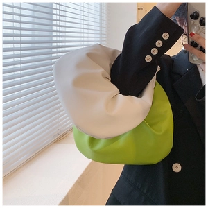 Detail of a minimalist knotted cloud bag in cream and neon green contrast PU leather