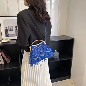 Detail of blue sequin evening bag with tassels and gold metal handle on a model