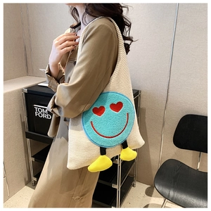 Detail of knit tote bag with large blue smiley face patch and heart-shaped red eyes