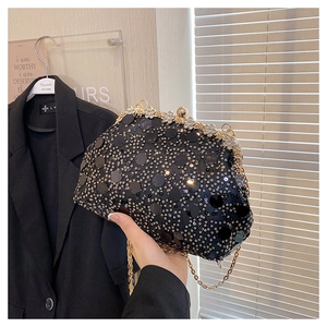 Détail macro des paillettes noires et broderies de perles dorées sur la pochette du soir
