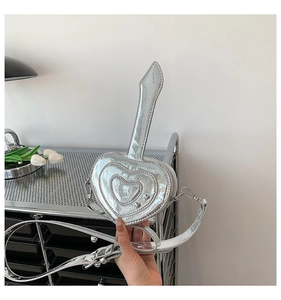 Dettaglio della mini borsa argentata a forma di cuore con finitura a specchio e tracolla