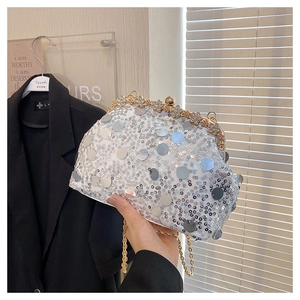 Détail d'une pochette de soirée à paillettes argentées avec fermoir fleur dorée et chaîne