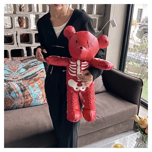 Close-up of a punk style red teddy bear backpack with white skeleton print and cross stitching