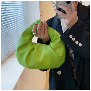 Detail of a green ruched leather handbag featuring a stylish knotted handle design