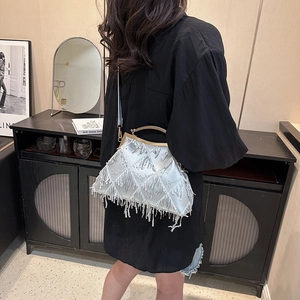 Silver sequin dinner clutch bag with fringe tassels and metal handle on a model