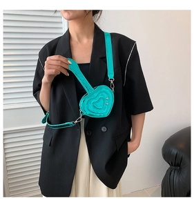 Dettaglio di una mini borsa a tracolla a forma di cuore verde metallizzato con cinturino