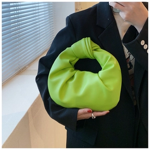 Detail of green pleated leather handbag with decorative knot handle and crescent moon shape