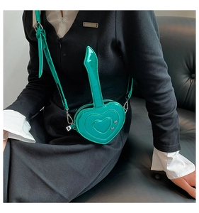 Borsa a tracolla a cuore verde lago mostrata su una modella su un divano in pelle