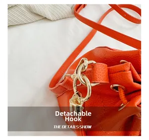 Detail of orange drawstring bucket bag with gold metal swivel hook and leather strap