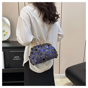Détail d'un sac de soirée à paillettes bleu foncé avec cristaux argentés et chaîne dorée