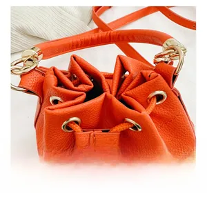 Macro shot of orange pebble grain leather drawstring bucket bag with gold hardware