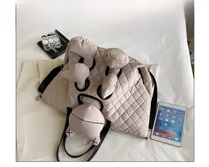 Detail of beige quilted tote bag with unique plush doll limbs and black adjustable strap