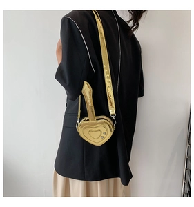 Vista laterale dettagliata di una mini borsa a tracolla dorata a cuore indossata da una modella