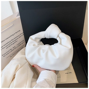 Close-up of creamy white pleated knot handbag in a luxury gift box packaging