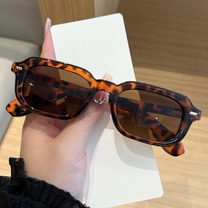 Detail of tortoise shell rectangular sunglasses with silver rivets and tinted lenses
