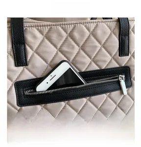 Detail of a large quilted tote bag featuring a secure back zippered pocket for a smartphone