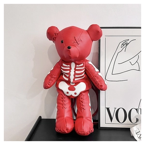 Macro shot of red leather gothic bear backpack with white skeleton embroidery details