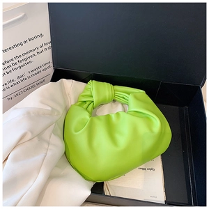 Detail of green ruched faux leather handbag featuring a knotted handle and soft pleats