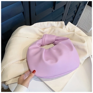 Close-up of a purple knotted handle hobo bag with pleated cloud texture on a beige suit