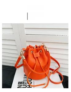 Detail of orange drawstring bucket bag featuring lychee grain leather and metal buckles