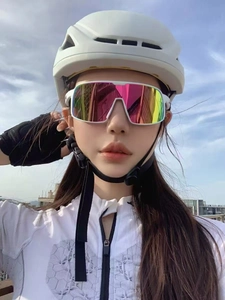 Close-up of white cycling helmet and colorful oversized sport sunglasses set against blue sky
