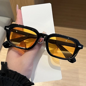 Detail of vintage rectangular black frame sunglasses with orange lenses and silver studs