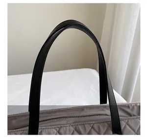 Detail of quilted nylon fabric and textured leather handle on the large shoulder bag