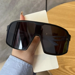 Macro view of oversized black wrap sunglasses with curved arms and dark protective lenses