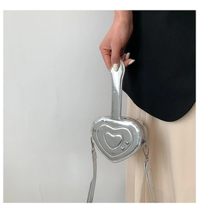Dettaglio della mini borsa argento a forma di cuore con finitura metallica e design