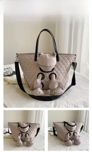 Detail of grey quilted nylon tote bag with cartoon plush and wide black shoulder strap