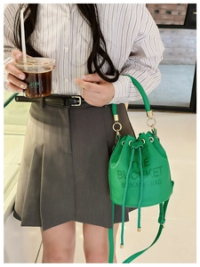 Close-up of bright green leather bucket bag with drawstring closure and brand engraving