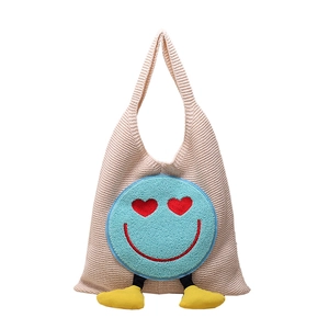Cute knitted tote bag with blue smiling face patch and small yellow feet details