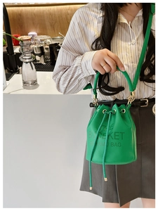 Close-up of emerald green leather bucket bag with drawstring and gold hardware detail