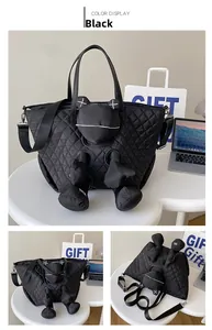 Detail of black quilted tote bag featuring a cartoon plush doll and dual carrying straps