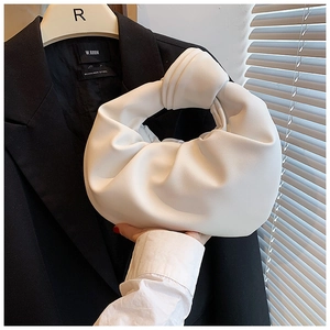 Detailed close-up of white knotted handle bag featuring soft pleated leather texture