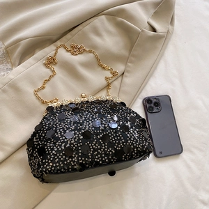 Pochette de soirée noire à paillettes avec chaîne dorée et fermoir strass sur tissu beige