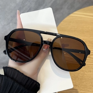 Detail shot of black oversized sunglasses featuring a stylish double bridge and brown lenses