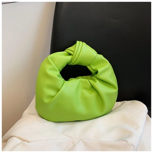 Detail of neon green knot handle handbag with pleated cloud texture on white fabric