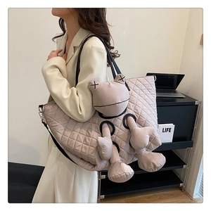 Detailed view of beige quilted tote bag featuring creative cartoon frog doll and wide strap