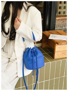Blue drawstring bucket bag with litchi grain texture and gold metal ring hardware