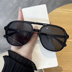 Close-up of black oversized aviator sunglasses with a classic double bridge design