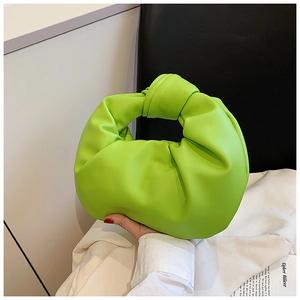 Detail of green ruched cloud bag with knotted handle and premium soft leather texture