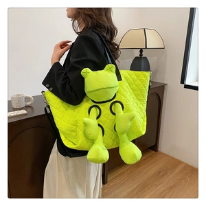 Detail of neon green quilted tote bag with 3D frog plush and black strap on model