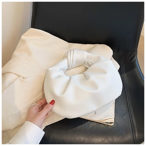 Detail of white knotted cloud bag showing matte leather texture and elegant pleats