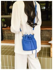 Royal blue drawstring bucket bag with textured leather grain shown on a model
