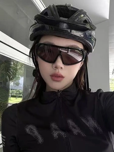 Close-up of stylish oversized sunshades and a professional black cycling helmet on a model