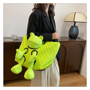 Detail of green quilted tote bag featuring creative frog plush doll with X eyes decoration