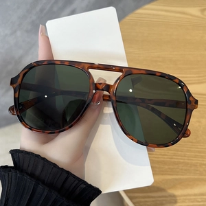 Detailed view of tortoiseshell pilot sunglasses with double bridge and dark green lenses
